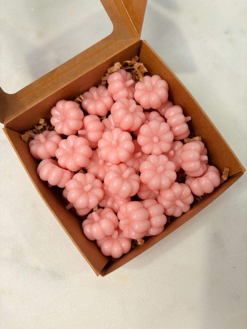 A pink wax melt shaped like a pumpkin beginning to melt in a wax warmer. A subtle shimmer emerges from the melt, creating a sparkling effect as the pink liquid softens.
